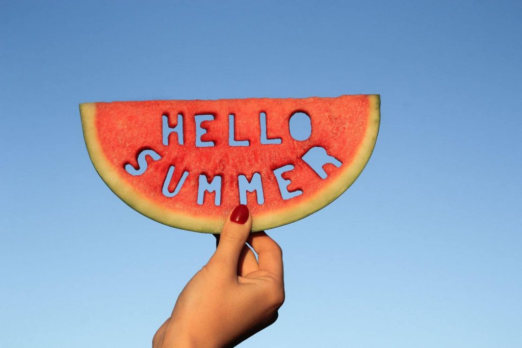 hand holding a piece of watermelon that says hello summer