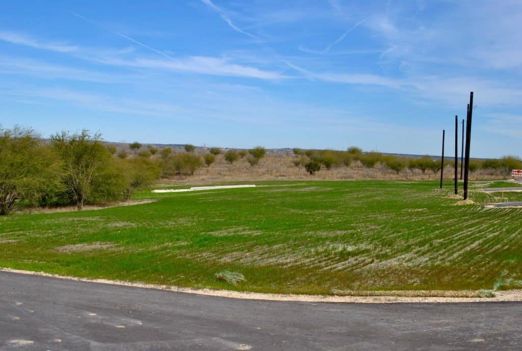 large grassy field with a road in the background