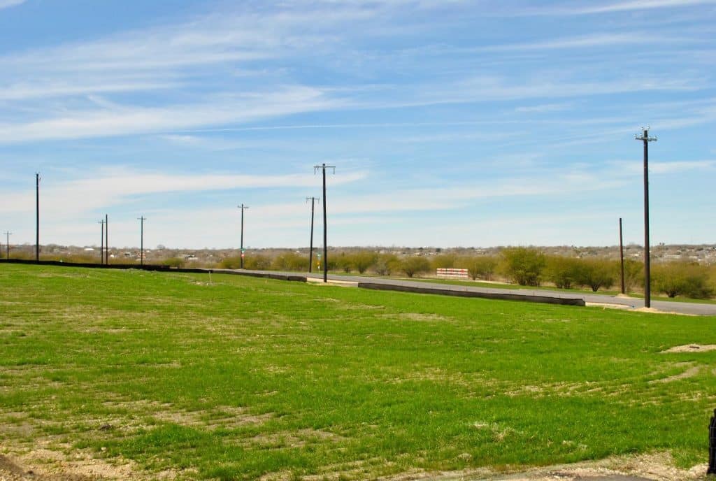 a grassy field with a road in the background
