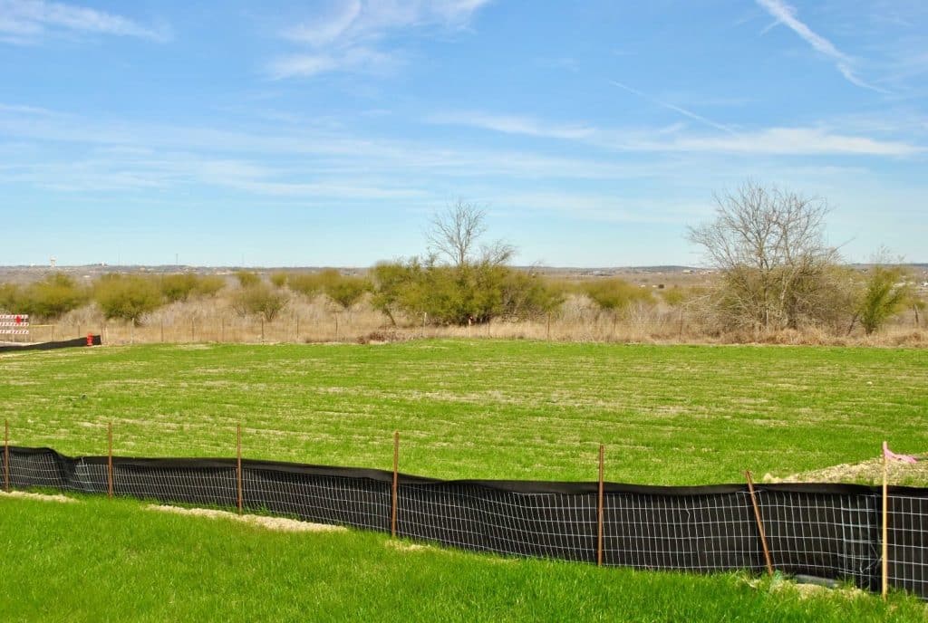 fenced in green field and tress in the background