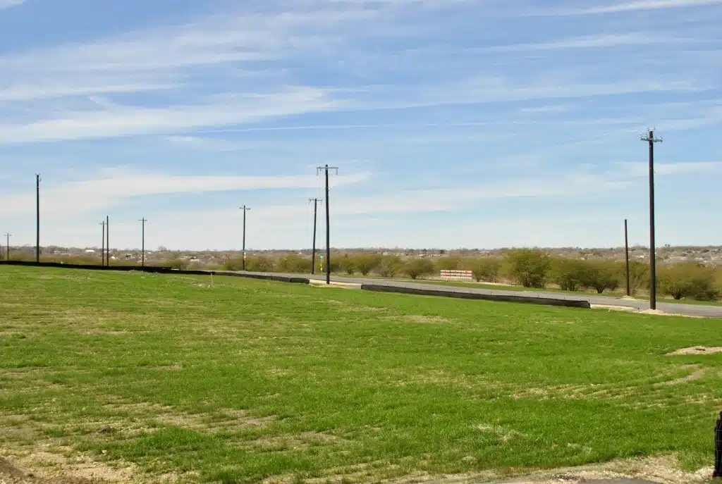 a grassy field with a road in the background