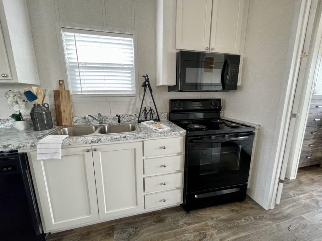 beautiful tiny mobile home kitchen with white cabinet and window with sink and stove wide angel