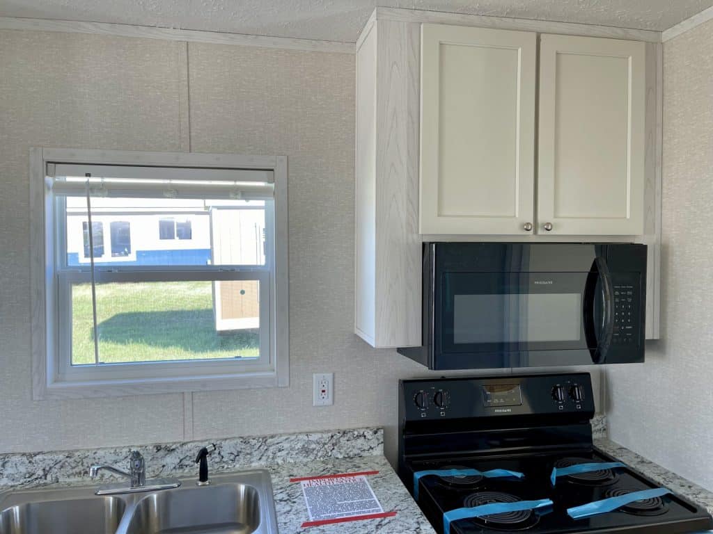 beautiful tiny mobile home kitchen with white cabinet and window