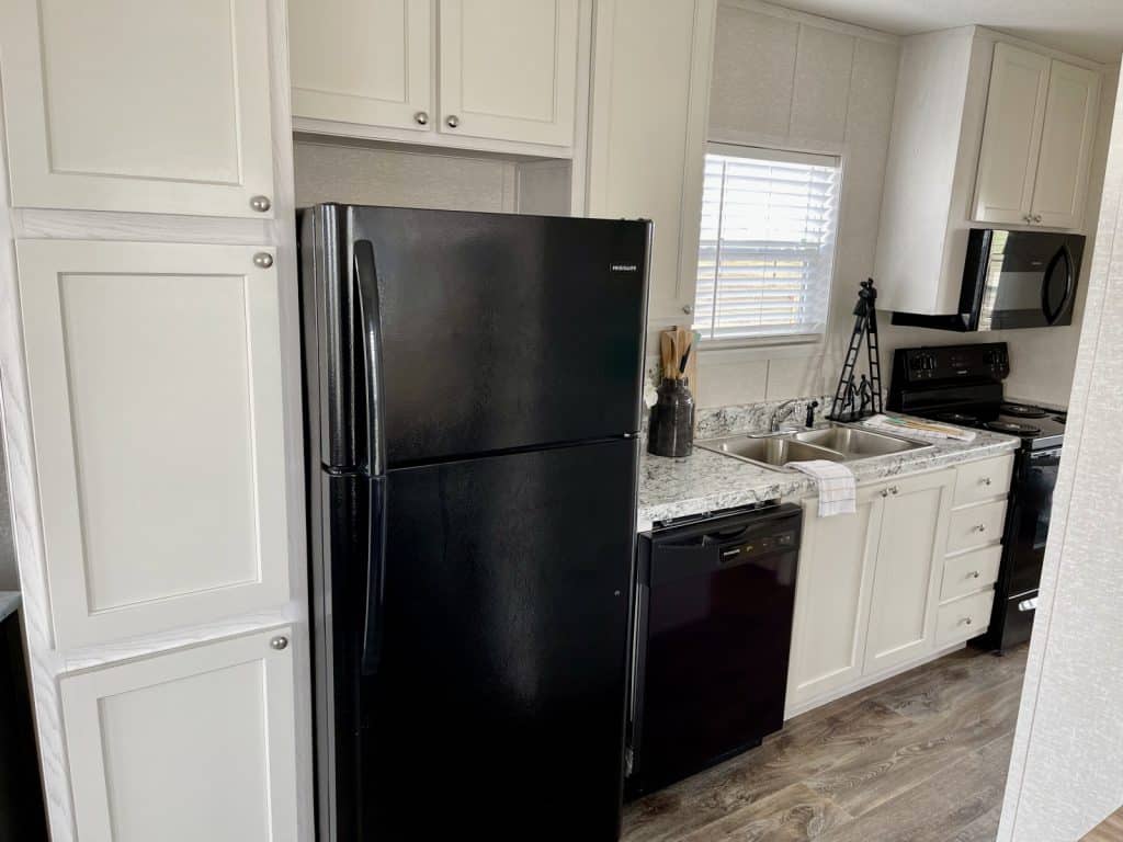 a black refrigerator inside of a kitchen with sink for dishwasher